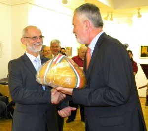 Páva Zsolt pécsi polgármester (jobbról) átnyújtja Bognár Levente aradi alpolgármesternek a reggel Pécsett sütött Magyarok kenyerét